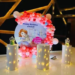 A magical "Princess Chehak" birthday party with a Sofia the First themed backdrop, a pink and red balloon arch, and illuminated pedestals.
