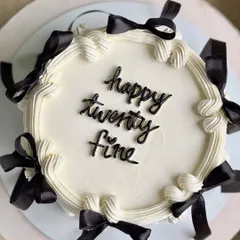 An overhead shot of the "happy twenty fine" cake, with its playful script and a perfect circle of black bows, creating a chic and celebratory design.