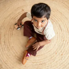 A candid moment from a multi-generational shoot. The little boy looks up at the camera while playing with a toy car, surrounded by his loving family.