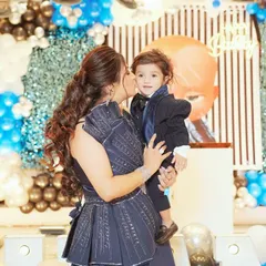 A mother's love captured in a single frame. This sweet, unposed photo shows a mother giving her son a kiss during his birthday celebration, a memory to cherish forever.