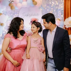 A heartwarming family portrait taken at a 5th birthday party. The parents look lovingly at their daughter, capturing a perfect family moment amidst the celebration.