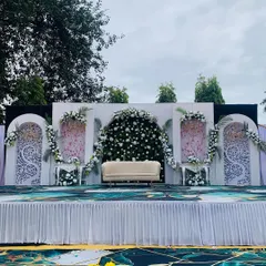 For this outdoor engagement, we designed a modern and elegant stage. The backdrop features intricate white jali panels, a central arch overflowing with white roses, and a clean, contemporary feel perfect for a sophisticated celebration.