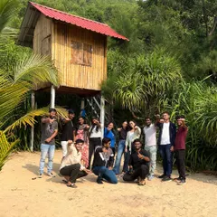 Our group posing in front of a cool treehouse on the beach, a unique find during our coastal exploration.