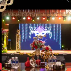 For a corporate celebration, I designed this entire masquerade ball theme. The setup included a custom stage with a large LED screen displaying thematic graphics, professional lighting trusses, and elegant table arrangements to create a mysterious and beautiful atmosphere.