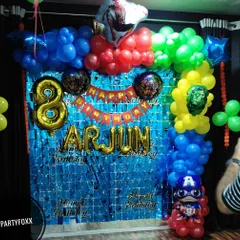 An Avengers-themed birthday party at home for Arjun's 8th birthday. This compact setup includes a blue fringe backdrop and a balloon arch with superhero accents.
