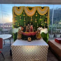 Even a simple ceremony can be made divine. Here, we created a beautiful outdoor altar with a backdrop of fresh banana leaves and garlands of white and yellow flowers, perfectly framing the deities against the evening sky.