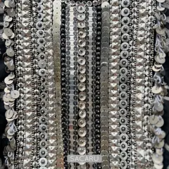 A detailed view of the exquisite hand embroidery on one of our statement necklines. This piece features meticulously arranged silver metal sequins and beads, creating a dense, glittering texture that exemplifies our commitment to intricate craftsmanship and luxurious detail.