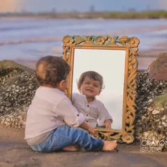A toddler discovers his own reflection in a vintage mirror on the beach. A beautiful, introspective moment captured by the sea.
