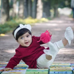Play isn't just about fun; it's about experimenting and discovering the world. This photo captures a baby's joyful play on a mat during an outdoor kids photoshoot.