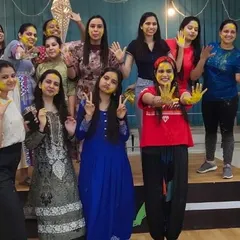 The whole group posing after a fun-filled Holi dance session, with faces smeared with festive colors.