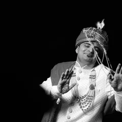 A fun and stylish black and white portrait of the groom. His playful "tashan" or swag-filled pose shows his personality and excitement on the wedding day.