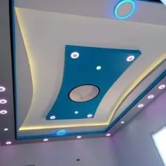 A beautiful ceiling design that combines soft curves with a bright blue color. The integrated spotlights and circular lighting elements provide excellent, balanced illumination.