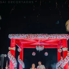 A magical moment under the wedding mandap as fireworks light up the night sky. This image captures the couple during their ceremony in our beautifully decorated red floral mandap.