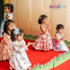 Young girls in beautiful dresses clap along to a performance on Grandparents' Day. Their joyful participation is what makes these events so special.