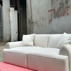 The full sofa shown against an industrial-style wall, demonstrating its versatility in different interior settings.