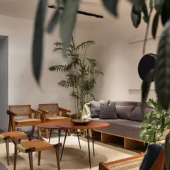 The living area of our 'Rustic Minimal' apartment project in Bangalore, designed for a young couple. We used a neutral palette of cement floors and mahogany wood furniture to create a warm, gallery-like feel. This space is filled with natural light and indoor plants, reflecting our love for biophilic design that brings the calming presence of nature indoors.