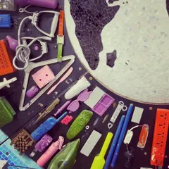 A close-up view reveals the individual items that make up the mural. You can spot things like old irons, remote controls, clothes hangers, and plastic toys, each with its own history.