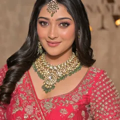 A smiling portrait showcasing a heavy Kundan and pearl necklace with a matching maang tikka. This set exudes traditional elegance.
