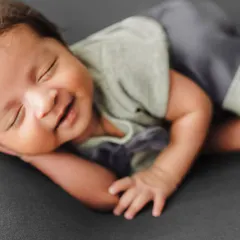 A heartwarming shot of a sleeping newborn with a gentle smile, demonstrating how to capture fleeting expressions.