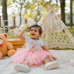 An outdoor first birthday picnic is a wonderful way to celebrate. This little girl, in her adorable tutu, is all smiles surrounded by her favorite teddy bears and a cute teepee tent.