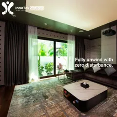 The same space can be a bright, airy living room by day. This image shows how our installations work with your home's natural light and decor, with heavy curtains ready to create a dark theater environment when needed.