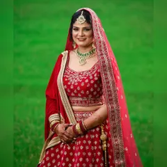 A classic bridal portrait of a bride in a stunning red lehenga, set against a vibrant green backdrop. I focused on creating a timeless image that highlights her elegance and the rich details of her wedding attire.