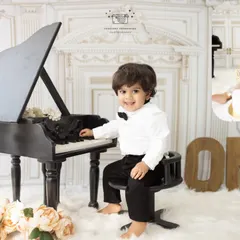 A little boy dressed in his best, sitting at a miniature grand piano for his first birthday shoot. This set also includes a classic cake smash for a fun ending.