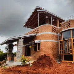 Here you can see the interplay of different materials, from the exposed brick and stone pillars to the sloped roofing. This view shows the home during the final stages of construction, surrounded by the natural landscape.
