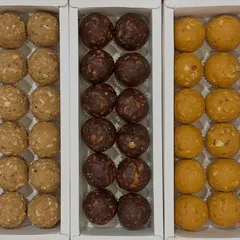 A trio of our best-selling homemade desi ghee laddoos. This image displays our classic Atta Panjiri, rich Date and Walnut (a sugar-free option), and traditional Besan laddoos, showing the variety available for your festive boxes.