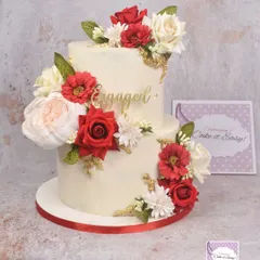 A classic two-tier engagement cake with a cascade of red and white flowers and subtle gold accents.