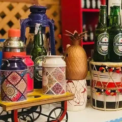 This setup combines rustic and traditional elements. A miniature cart, patterned canisters, and a dhol create a quirky and colorful corner at a Funjabi-themed event, perfect for serving beer or signature cocktails.