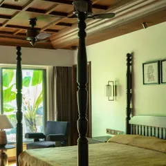 The master bedroom, featuring a classic four-poster bed and a coffered wooden ceiling. The design creates a sanctuary that is both grand and intimate, rooted in a timeless Indian aesthetic.