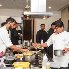 A busy moment on the line, with our chefs working together to plate dishes during a high-volume catering service. The organized chaos of a professional kitchen.