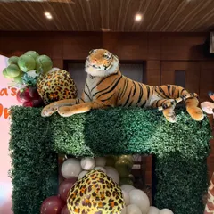 A close up of the details in our jungle theme decor, featuring a realistic tiger prop resting on a faux hedge. These elements make the theme more immersive and fun for kids.