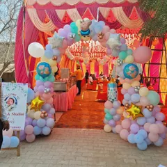 A large balloon archway creates a grand entrance for this outdoor tent party. The pastel colors and star foil balloons add a festive touch.