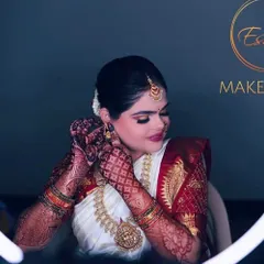 This bride is the picture of elegance for her muhurtham. The makeup features a classic red and white silk saree, intricate henna, and stunning temple jewellery.