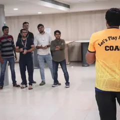A group of employees listening intently during a corporate team building event. Our coaches ensure everyone feels comfortable and ready to participate in the upcoming fitness challenges.