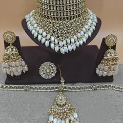 A stunning gold and pearl Kundan set with a wide choker, heavy jhumkas, and a matching maang tikka and ring.