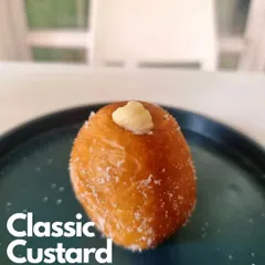 A close up of my Classic Custard Bomboloni. This perfectly fried doughnut is filled with a smooth, luscious vanilla custard, a timeless and comforting flavor.