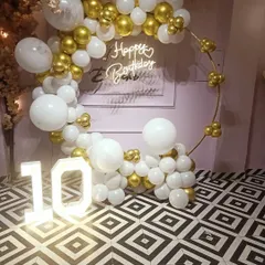 A simple yet very classy ring decoration for a 10th birthday party at home. The white and gold chrome balloons, paired with a neon sign and light-up numbers, create a sophisticated look.