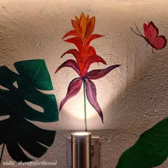The uplighting on the wall highlights a tropical flower and butterfly, adding drama and drawing attention to the smaller, delicate details of the balcony mural.