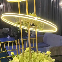 A modern and stylish centerpiece with a unique illuminated ring structure. The base is filled with baby's breath and yellow roses, adding a soft, floral touch.