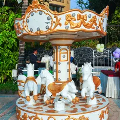 This elegant white and gold carousel adds a touch of classic charm and magic to any party. It's a beautiful ride that doubles as a stunning photo opportunity for princess or carnival themes.