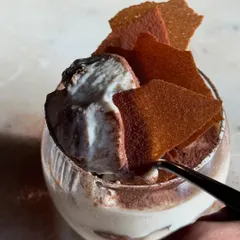A spoonful of our Tiramisu, showcasing its light, creamy texture and the crisp shards on top.