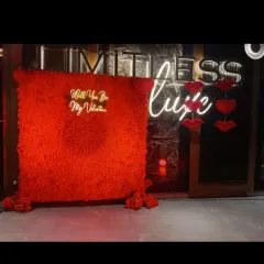 A bold and dramatic Valentine's backdrop. This features a wall covered in red flowers with a "Will You Be My Valentine" neon sign, creating a very passionate and immersive photo spot.