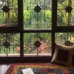 This wide window at the Roopa Hariprasad Residence features a custom-designed grille with floral motifs and inlaid tiles. It frames the view of the garden beautifully, turning the window itself into a piece of art.