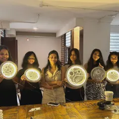 A group of proud students showing off the glowing moon lamps they created during a school workshop event at our cafe.