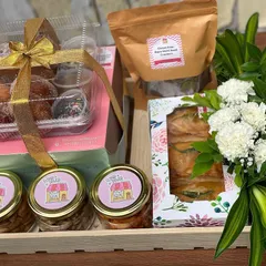 A beautiful custom hamper featuring a mix of my bestsellers. This one includes a mini donut box, jars of savoury snacks, baked vada pav puffs, and a bag of gluten-free crackers, all arranged in a wooden tray with fresh flowers.