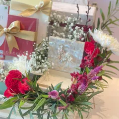 Another angle of our indulgent chocolate hamper, highlighting the lush floral arrangement of red carnations and white chrysanthemums that frames the gifts.