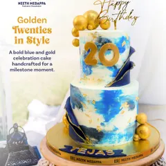 Entering a new decade calls for a cake that makes a statement. This two-tiered 20th birthday cake features a modern blue and white watercolor effect, accented with edible gold leaf, dramatic navy blue sails, and shimmering golden chocolate spheres for a touch of luxury.